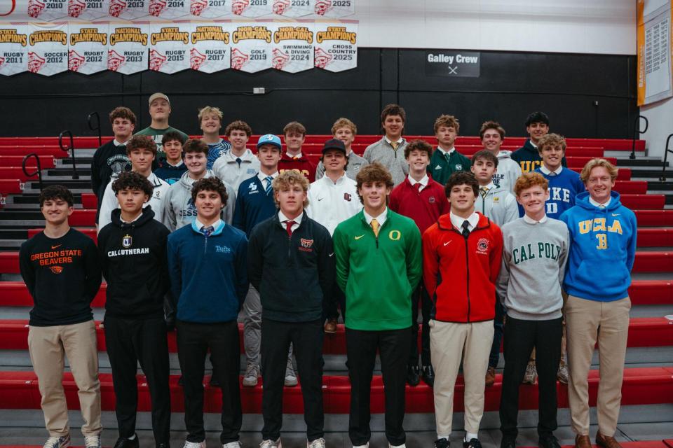 Group of seniors in college sweatshirts lined up in gym bleachers