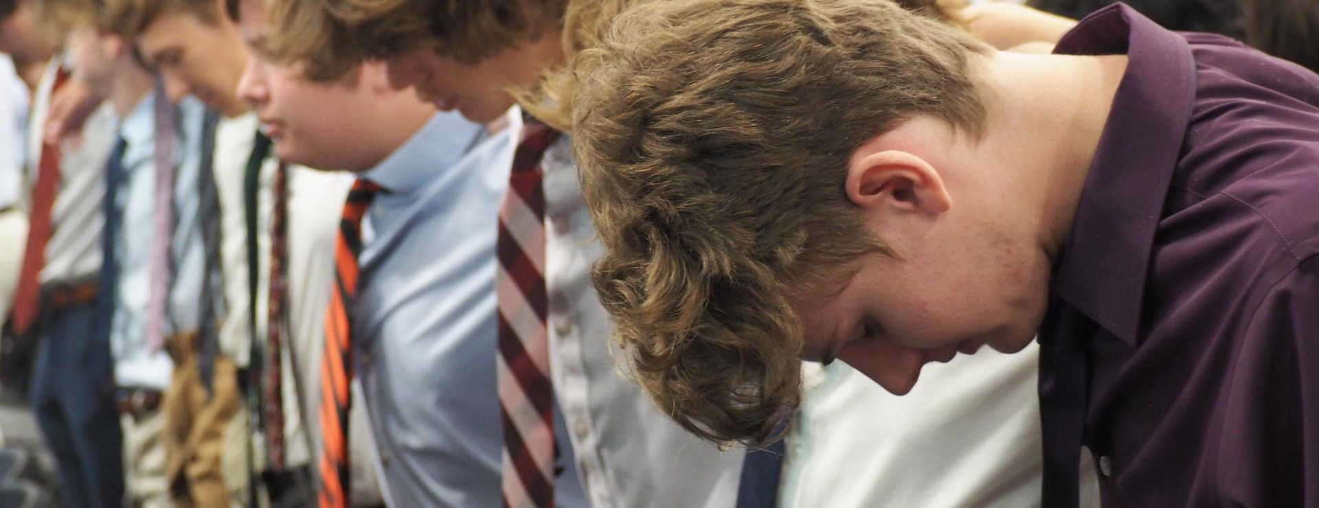 close up of students with heads bowed in prayer