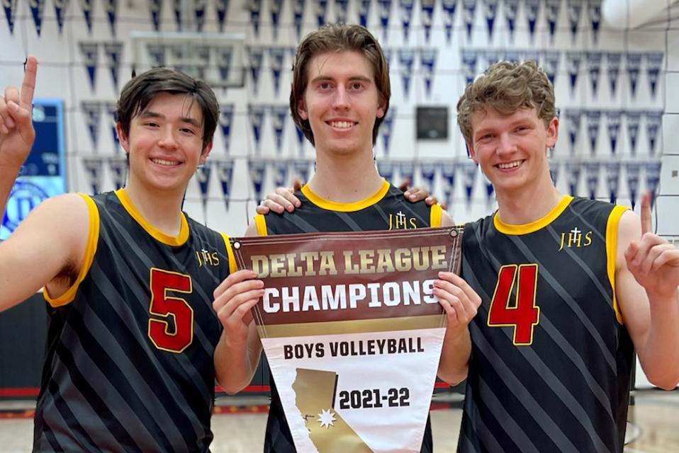 Three players smiling in gym holding a pennant