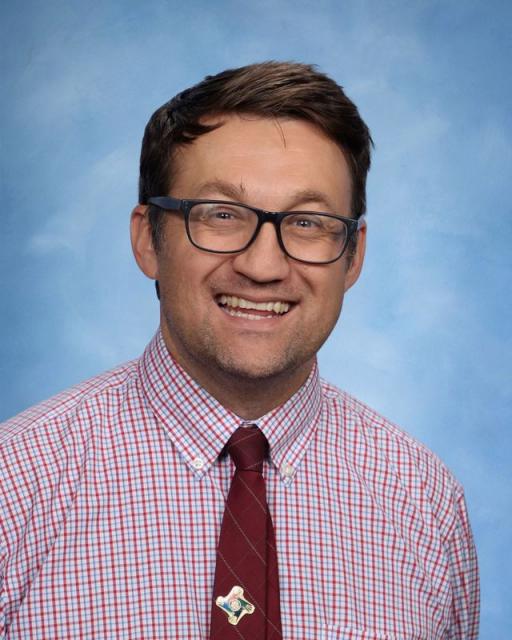 Studio head shot of smiling John in shirt and tie