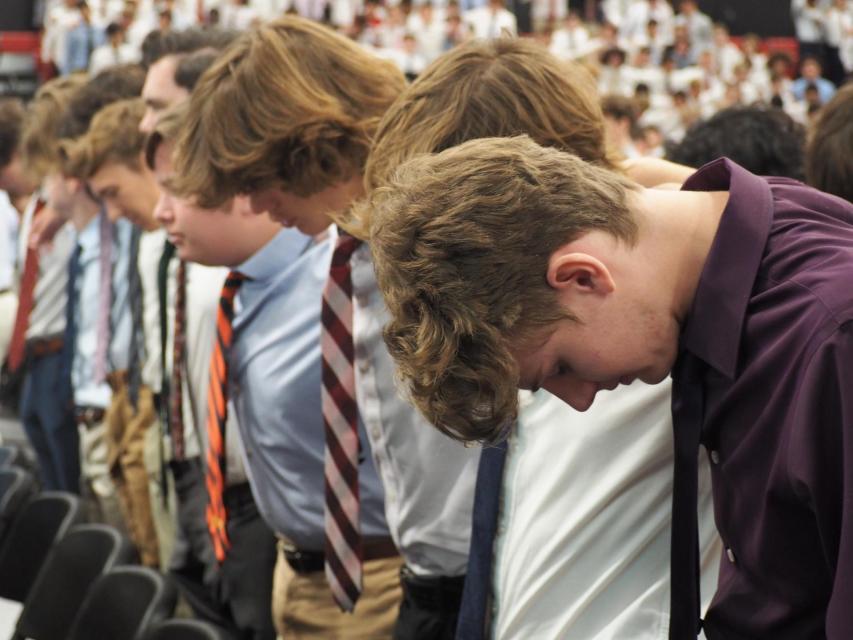 close up of students with heads bowed in prayer