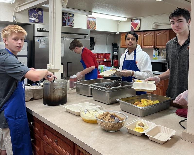 A group of student wearing aprons and prepping food in an industrial kitchen