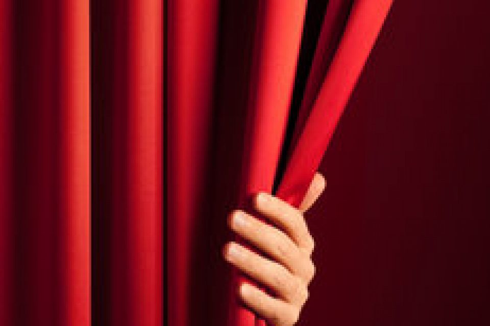 hand peeking around a red curtain