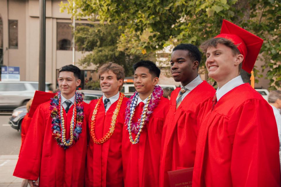 Graduates pose for a picture in red gowns after graduation