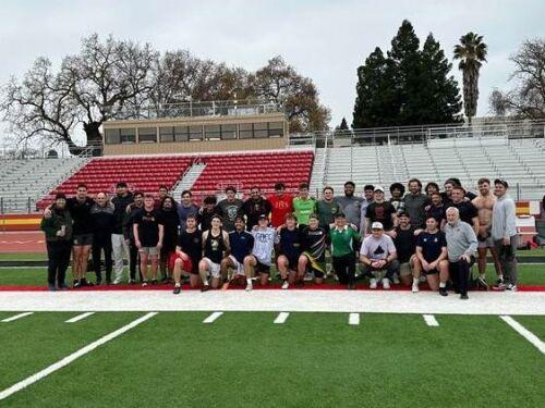 Group of alumni who came out to play lined up in front of the bleachers