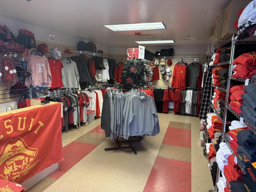 image of shirts, hats and sweatshirts on racks and shirts hanging on hangars inside  the store
